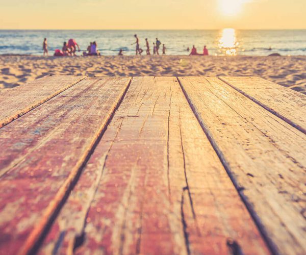 sandy wooden decking on the beach with people in the background